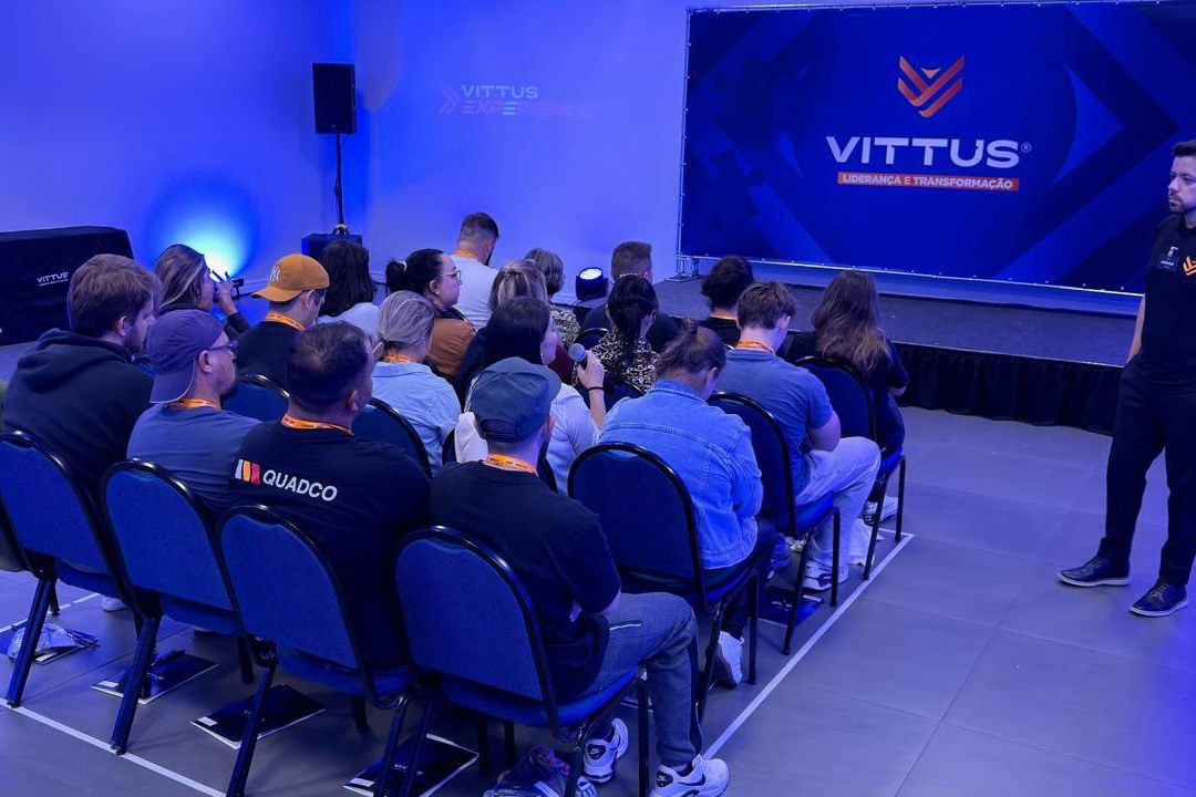 Turma sentada na sala da imersão Vittus Experience, com Jonas Silva ao lado do palco